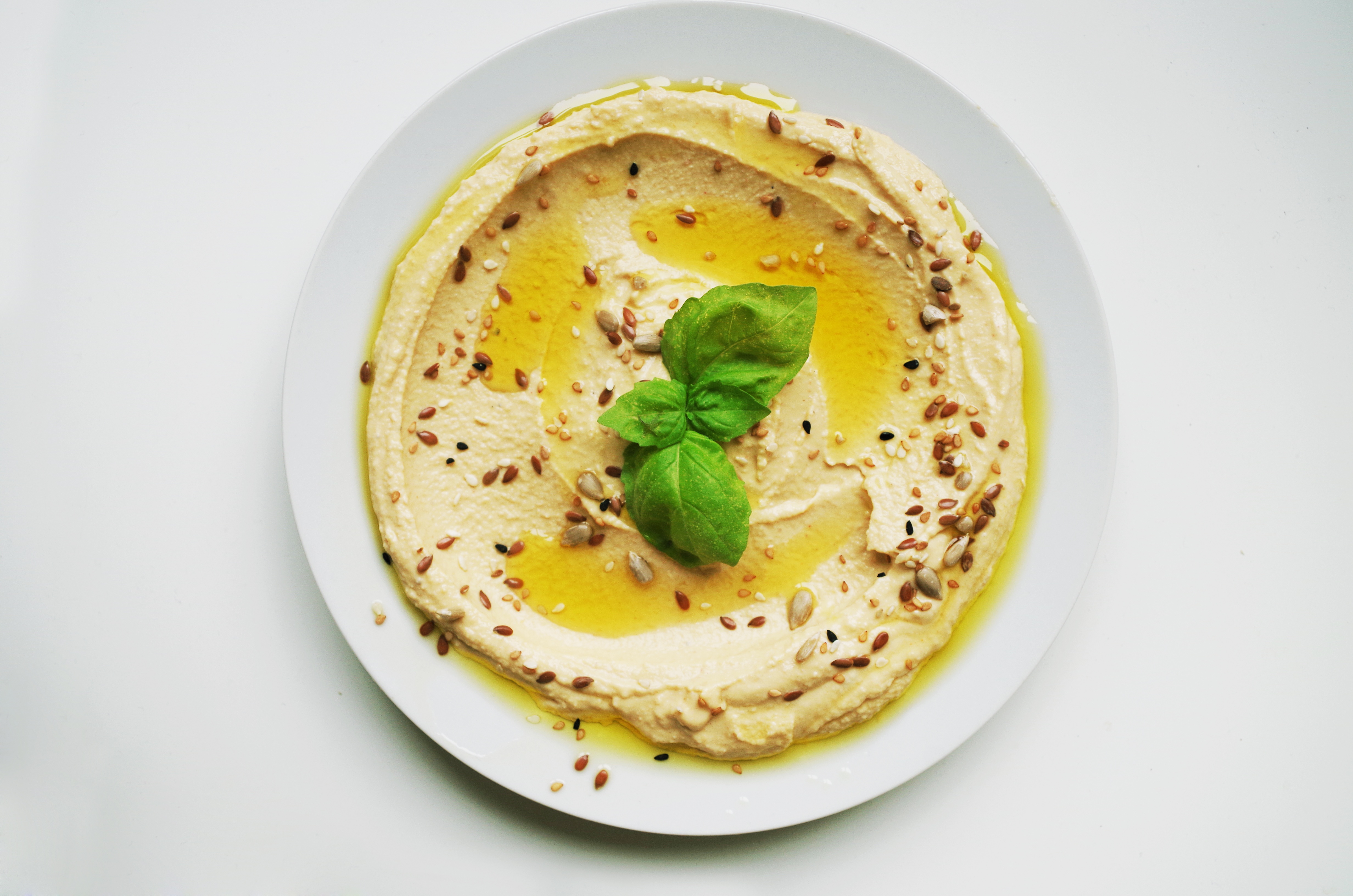 Hummus with oil and seeds on a white plate.
