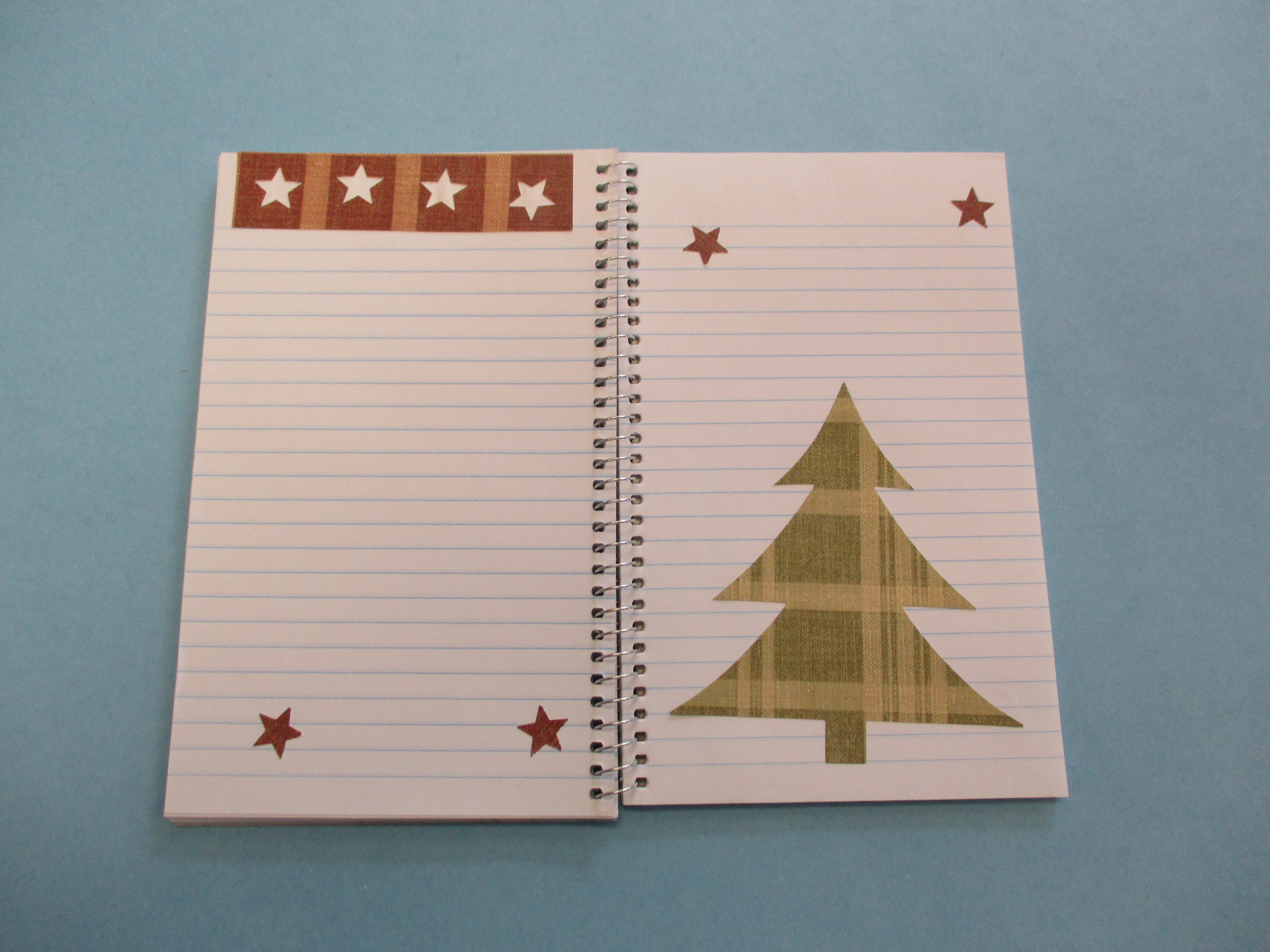 Spiral notebook open with stars and a Christmas tree inside.