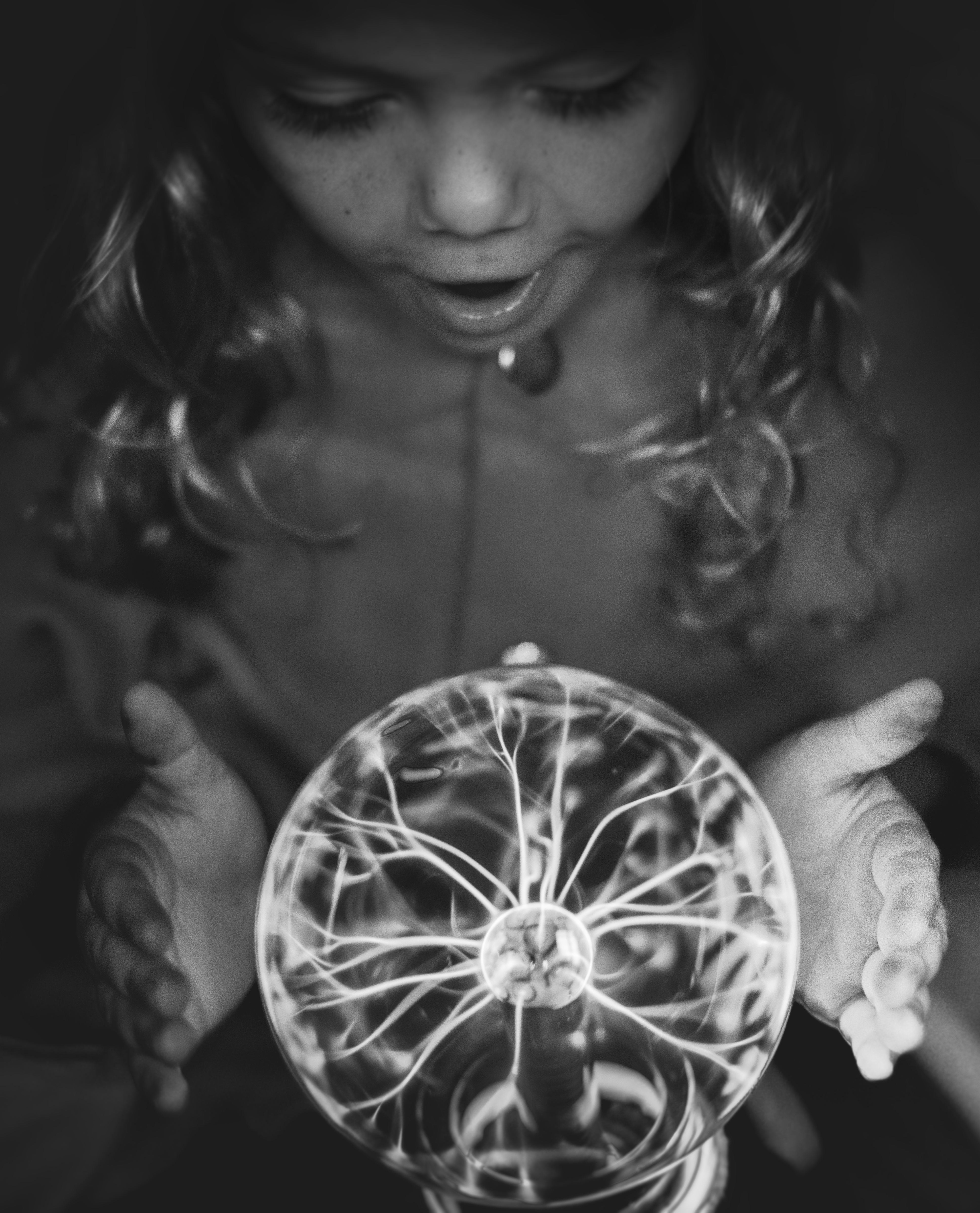 Black and white photo of a young girl fascinated by a plasma ball.