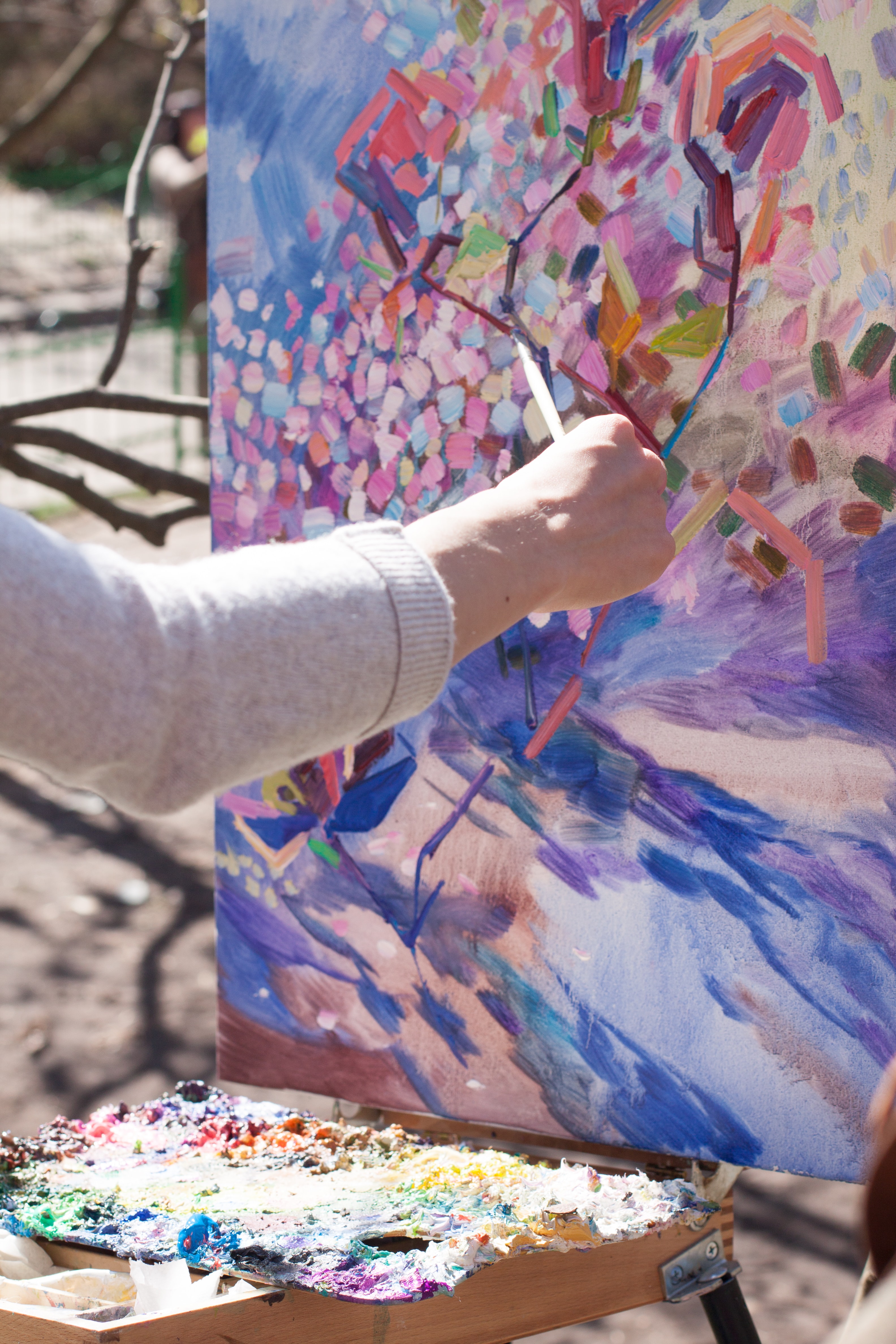 Person painting a pastel tree on canvas.