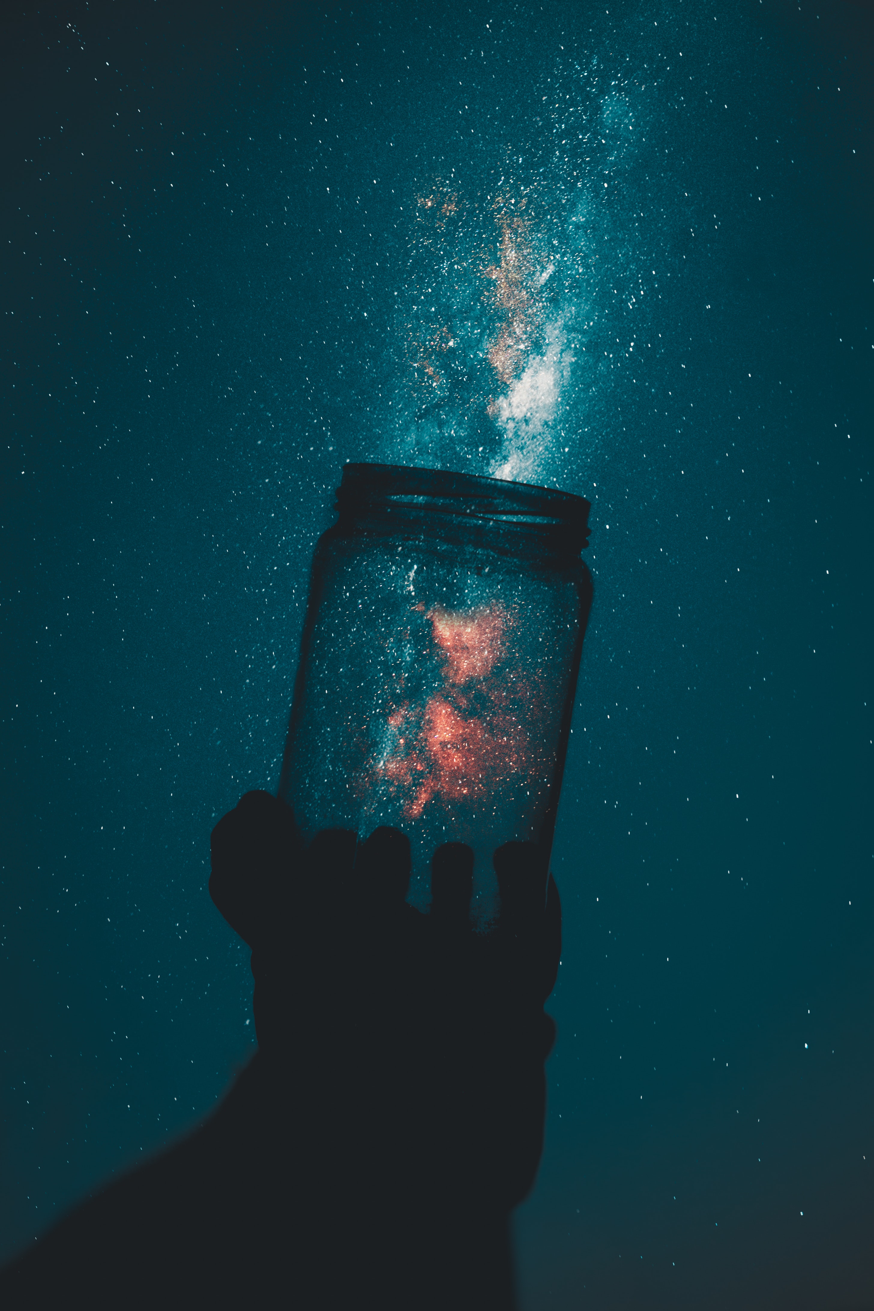 Hand holding a jar over a galaxy image.