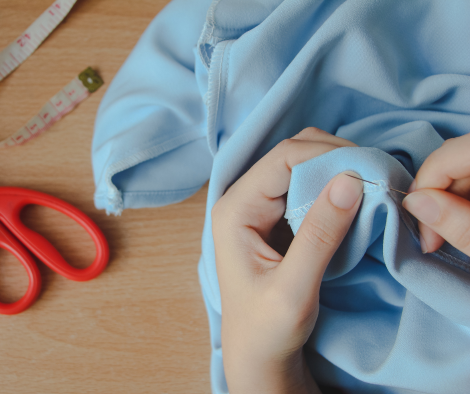 Image of a person stitching the seam in a light blue garment.