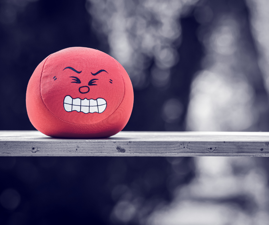 Red stress ball with a stressed expression on  a wood plank in a black and white picture.