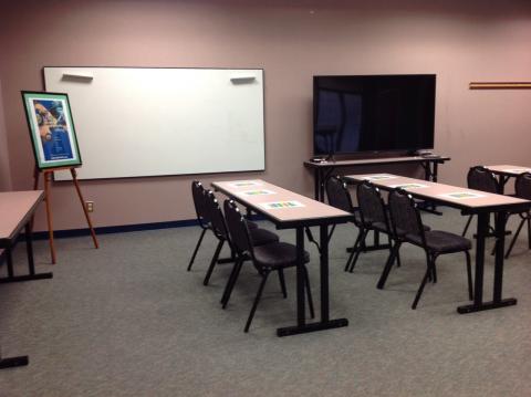 Moneta Community Room with classroom setup with whiteboard, easel, and tv