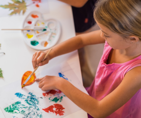 Child making leaf impressions with paint