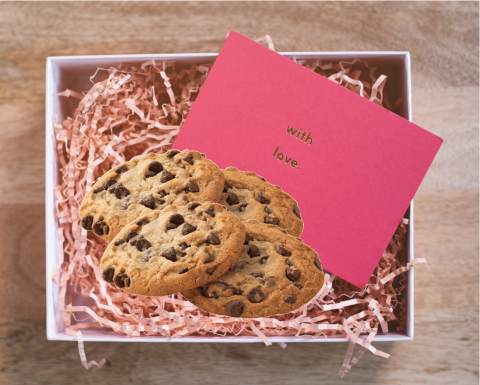 Cookies in a box with pink paper strips and a note that says with love.