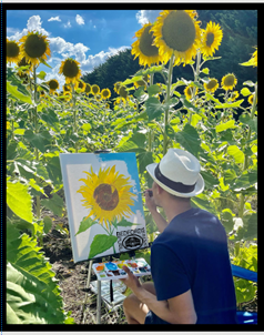 Man painting a sunflower in the middle of a field of sunflowers.