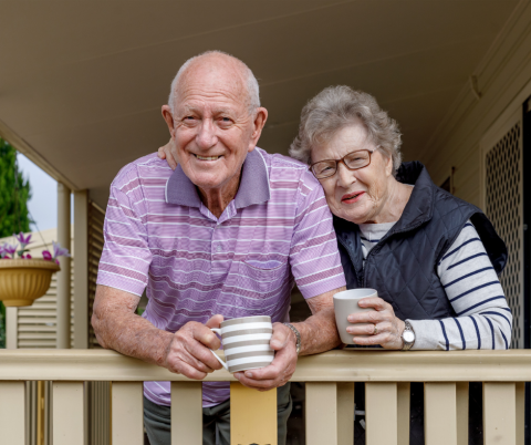 Senior couple on their porch holding coffee cups