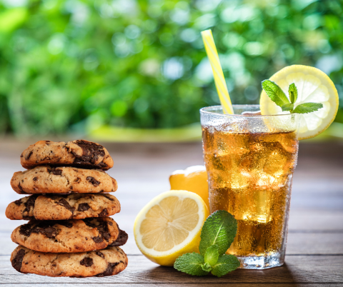 Glass of ice tea with lemons and a stack of chocolate chip cookies.