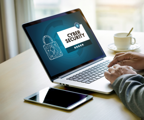 Mans hands on a laptop with a cybersecurity message on the screen.