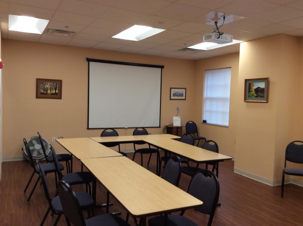 Peaks Room with tables, chairs, and a projector screen