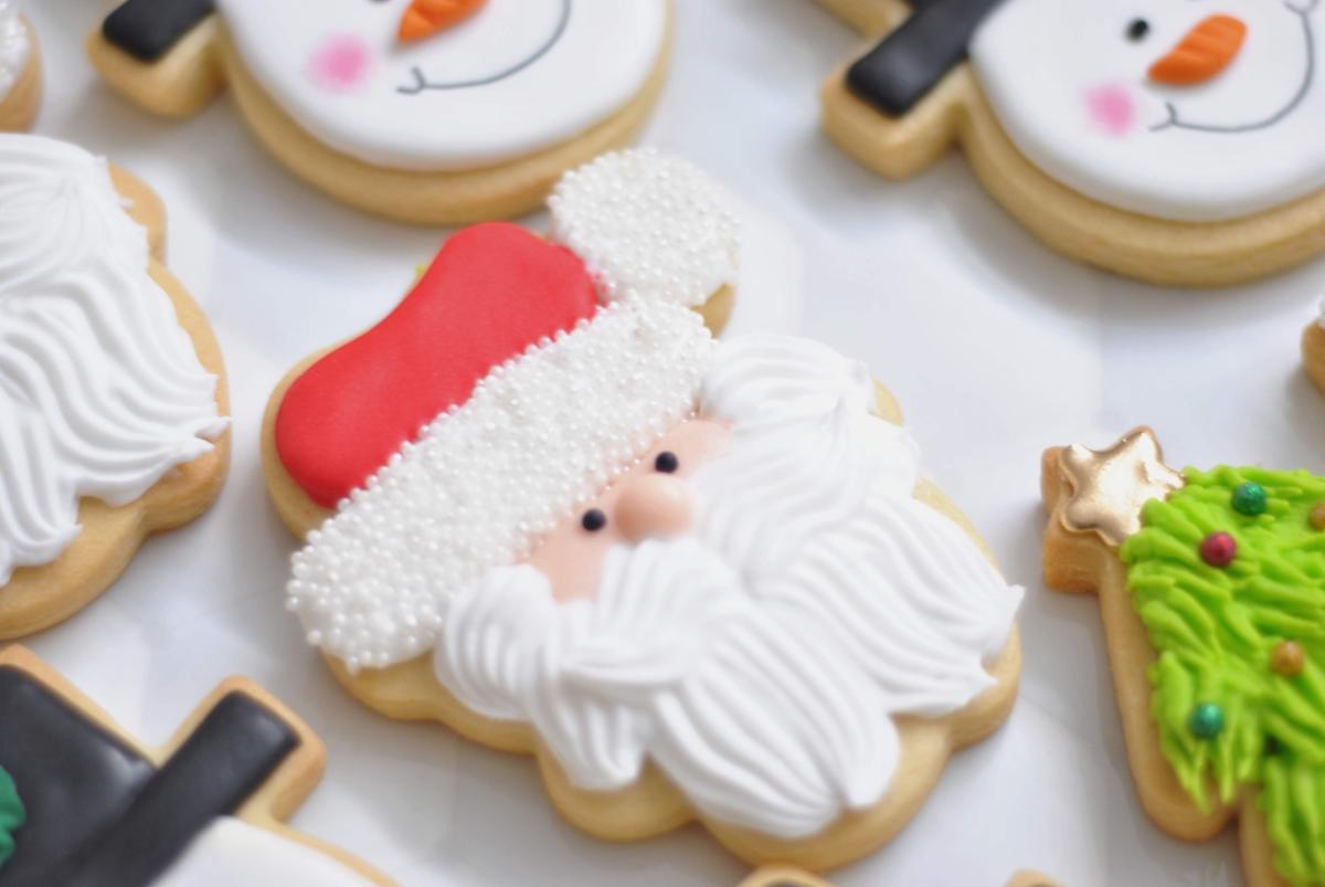 Fancy Christmas cookies decorated to look like Santa, a Snowman's Face, and a Christmas tree.