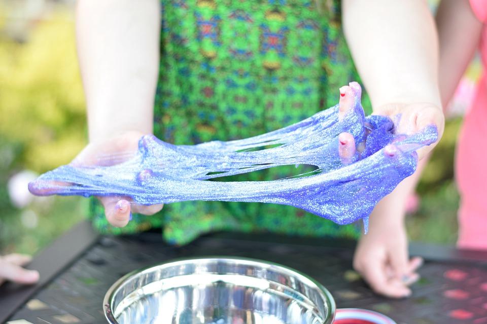 Girl stretching blue glitter slime.