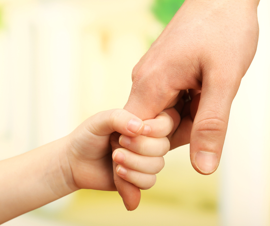 Small child's hand holding an adults hand.