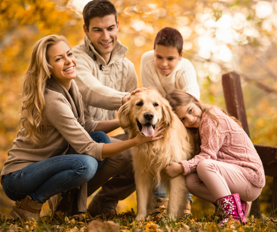 Photo of a mom, dad, son, and daughter with their dog in a Fall setting.