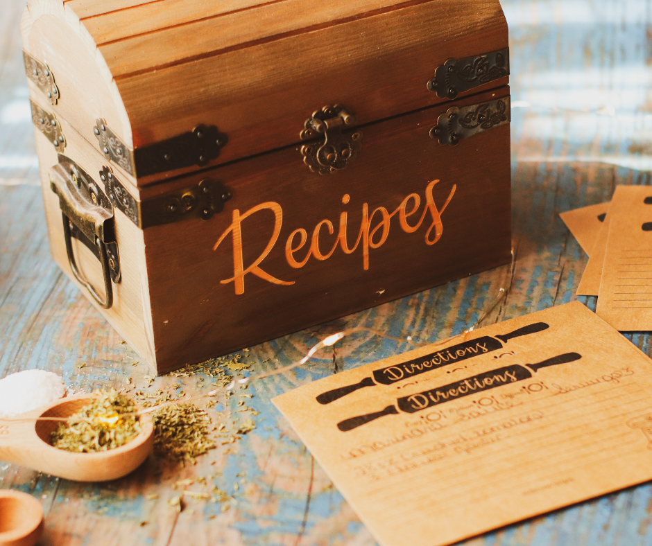 Box of recipes and recipe cards and a loose spice on a worn table.