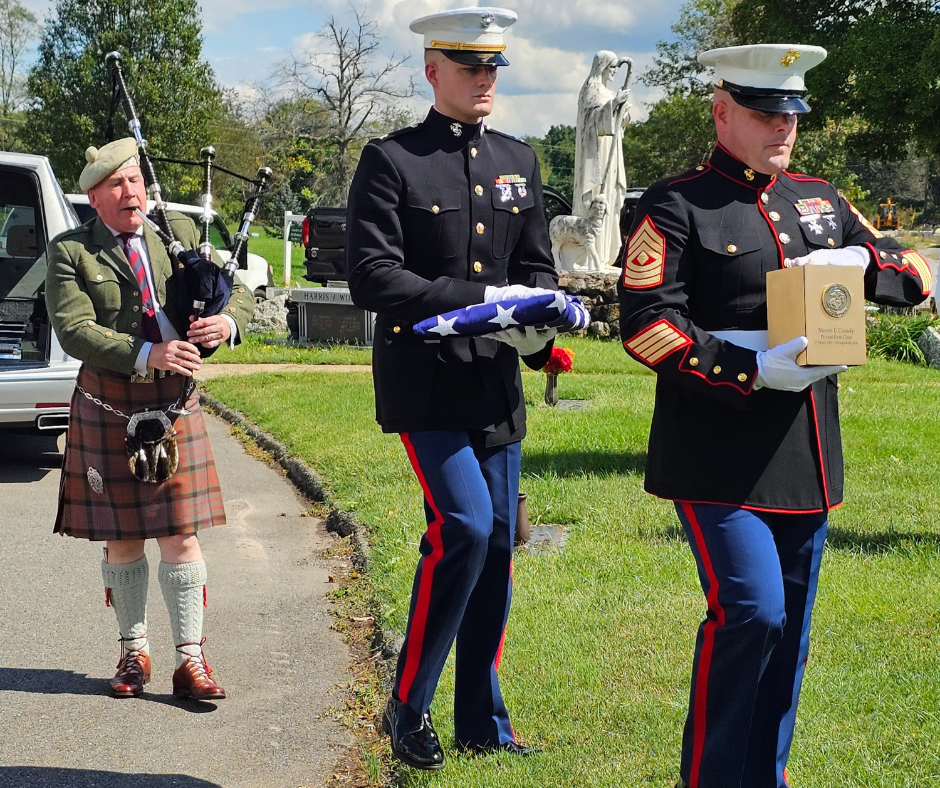 Marines presenting the remains of WWII Marine Morris E. Canady and a folded flag followed by a bagpiper.