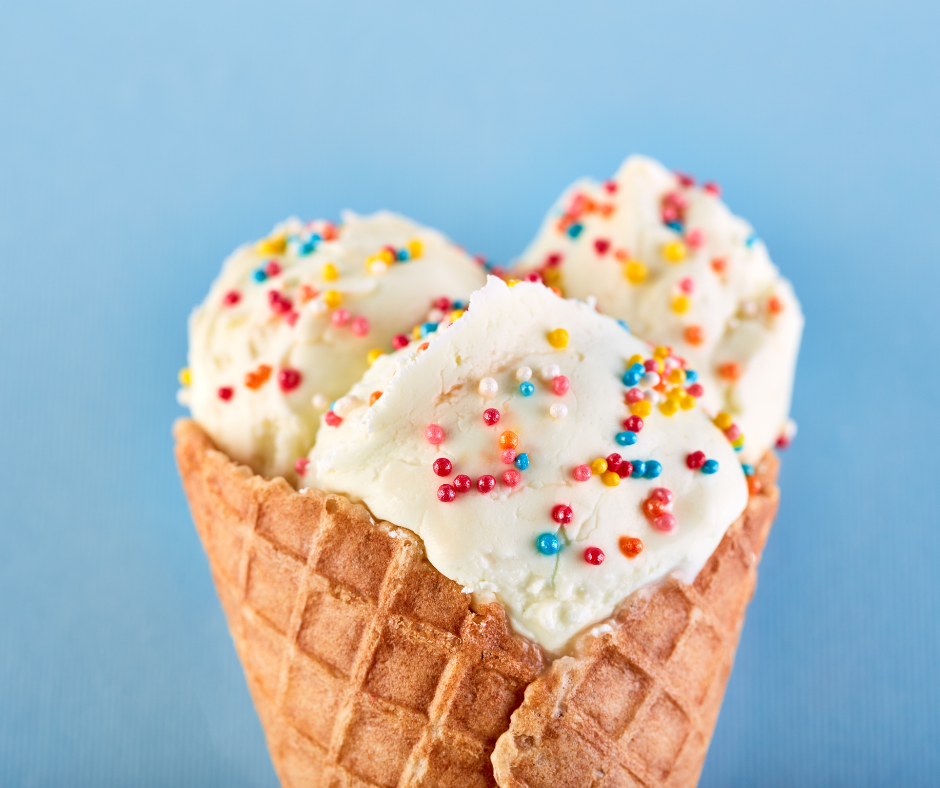 Vanilla ice cream and sprinkles in a waffle cone with a blue background.